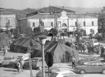 Una delle immagini simbolo  del terremoto ad Atripalda: la tendopoli allestita dai soldati in Piazza Umberto I e l’orologio della Dogana fermo alle 19:34